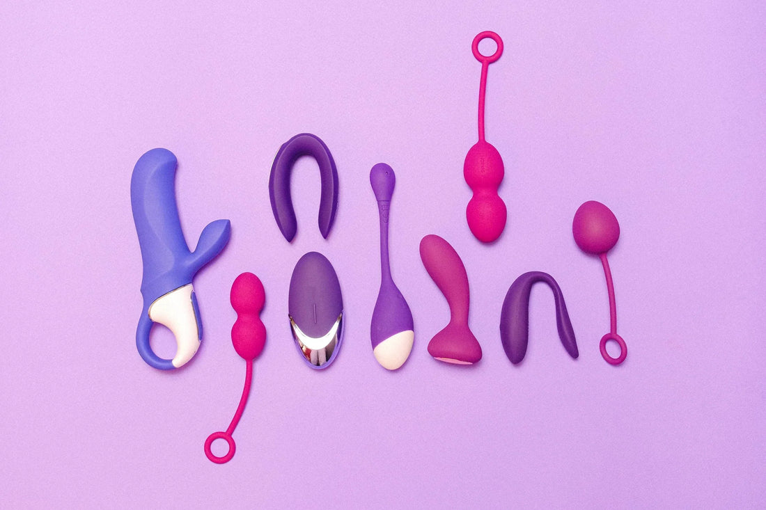 Sextoys violets et roses de différentes formes alignés sur un fond violet.