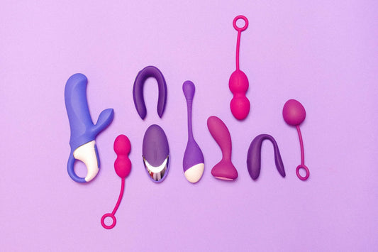 Sextoys violets et roses de différentes formes alignés sur un fond violet.