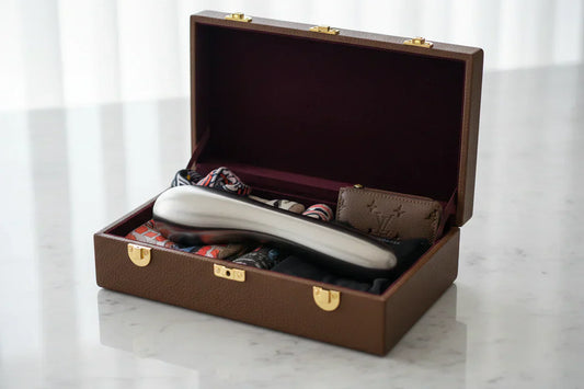 Valise ouverte sur une table contenant un objet métallique type masseur, avec des accessoires rangés à l’intérieur.